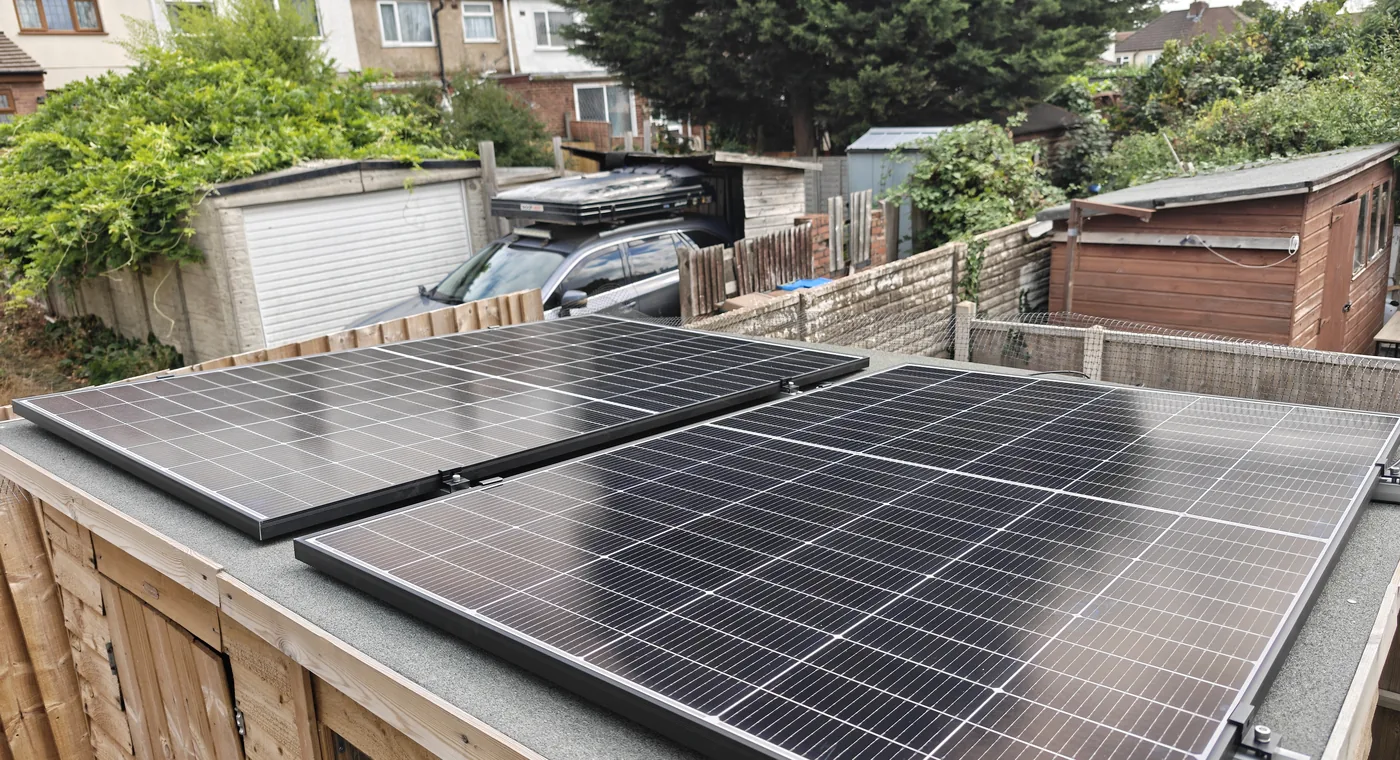 Two plug-in solar panels mounted on a garden store roof behind a terraced house in the UK