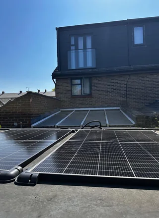 Plug-in solar panels on a flat roof behind a UK terraced house
